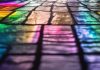 A photo of a slate floor covered in rainbow light that has filtered through a stained glass window.
