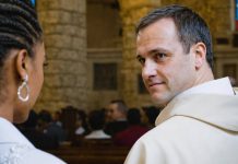 A male clergy member looking at a woman in a church.